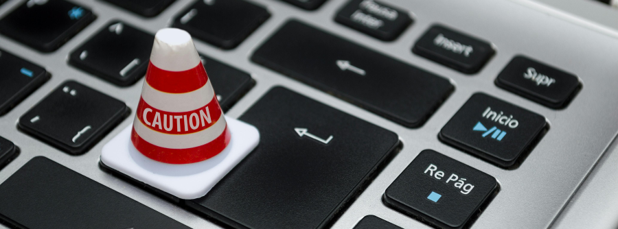 Image of a keyboard with a cone on it that has the word "caution" written on it